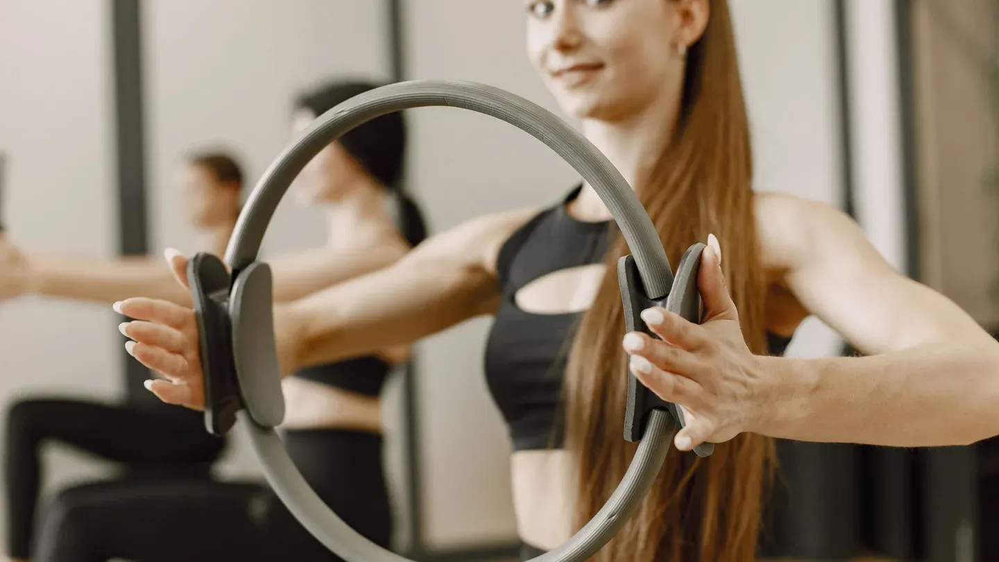 Mulher segurando anel de pilates (magic circle) durante exercício Mulher segurando anel de pilates (magic circle) durante exercício