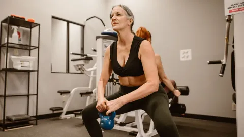 Mulher fazendo agachamento com kettlebell em treino funcional