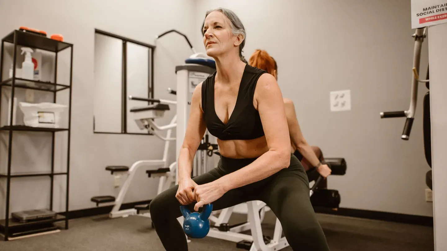 Mulher fazendo agachamento com kettlebell em treino funcional