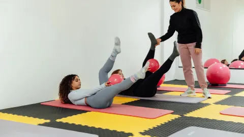 Duas mulheres alongando em tapetes durante aula de pilates