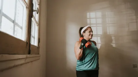 Mulher madura treinando força com halteres em casa