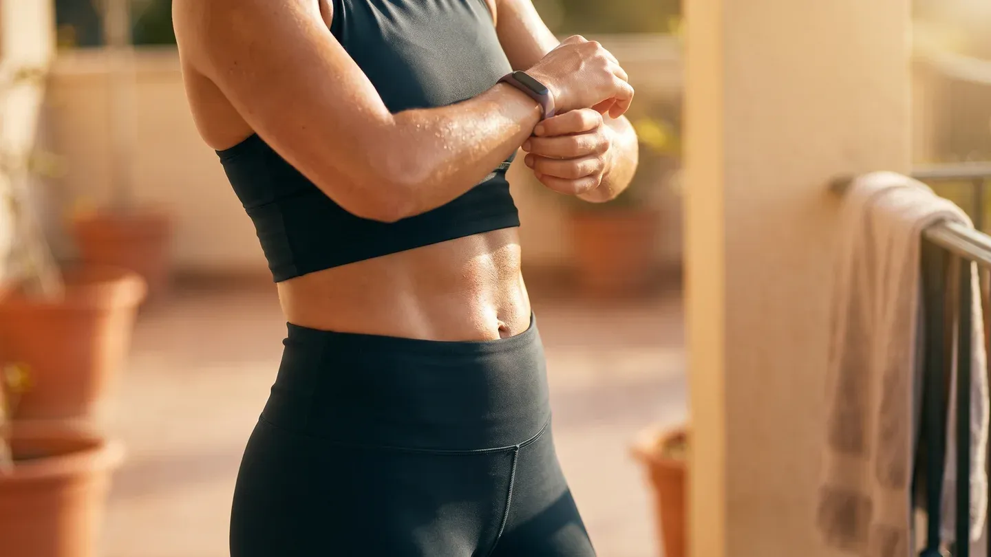 Mulher ajustando o smartwatch após treino intenso na varanda de casa Mulher ajustando o smartwatch após treino intenso na varanda de casa