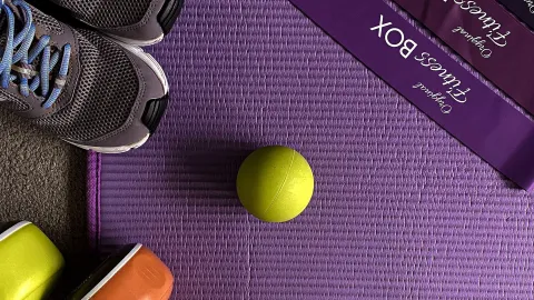 Tênis, elásticos de resistência e bola sobre tapete de exercícios