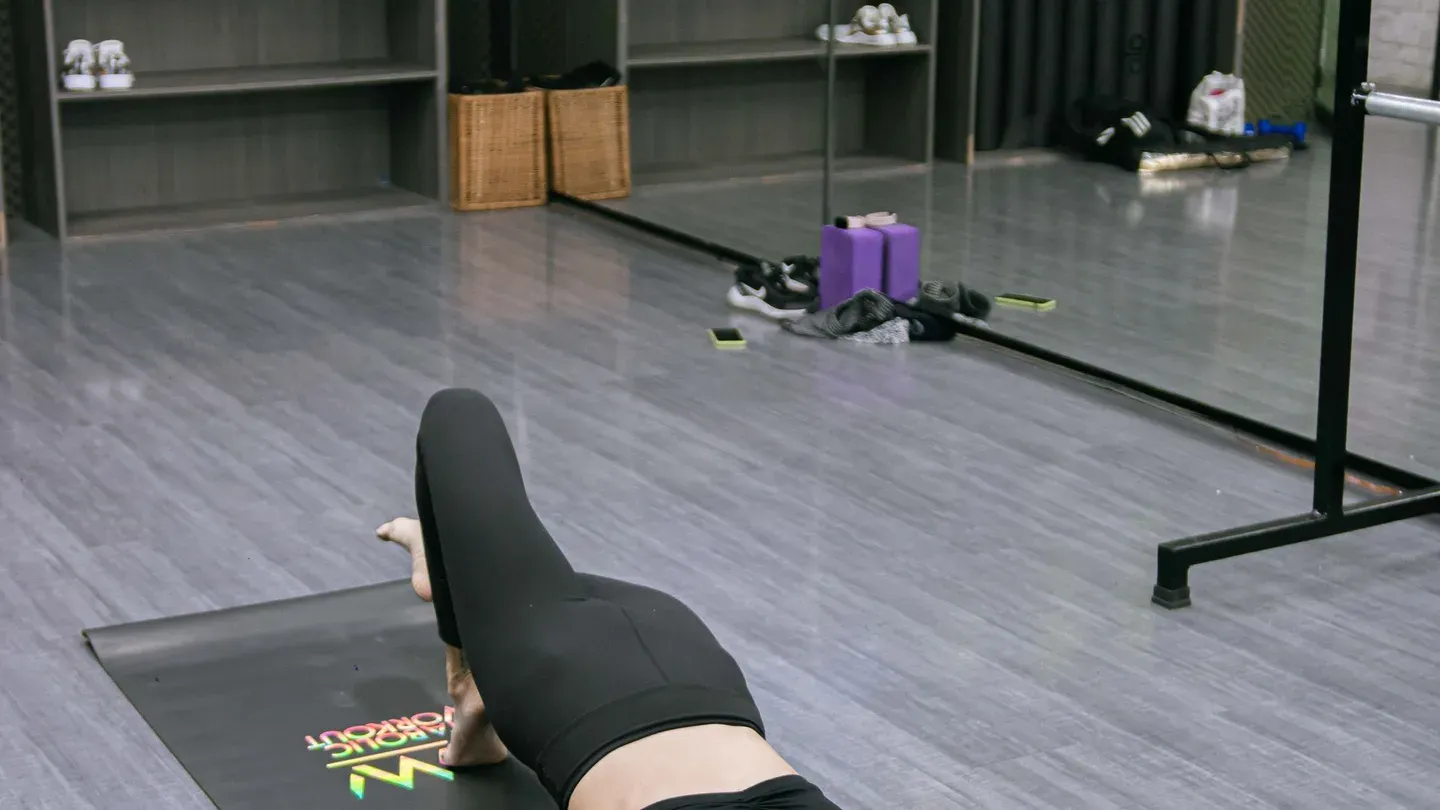 Mulher praticando pilates com bola em estúdio com equipamentos ao fundo Mulher praticando pilates com bola em estúdio com equipamentos ao fundo