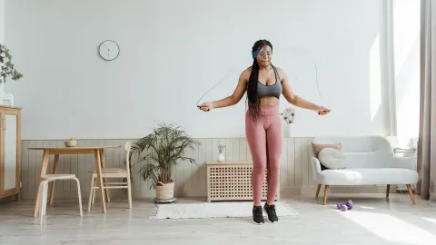 Mulher pulando corda na sala de casa durante treino cardio