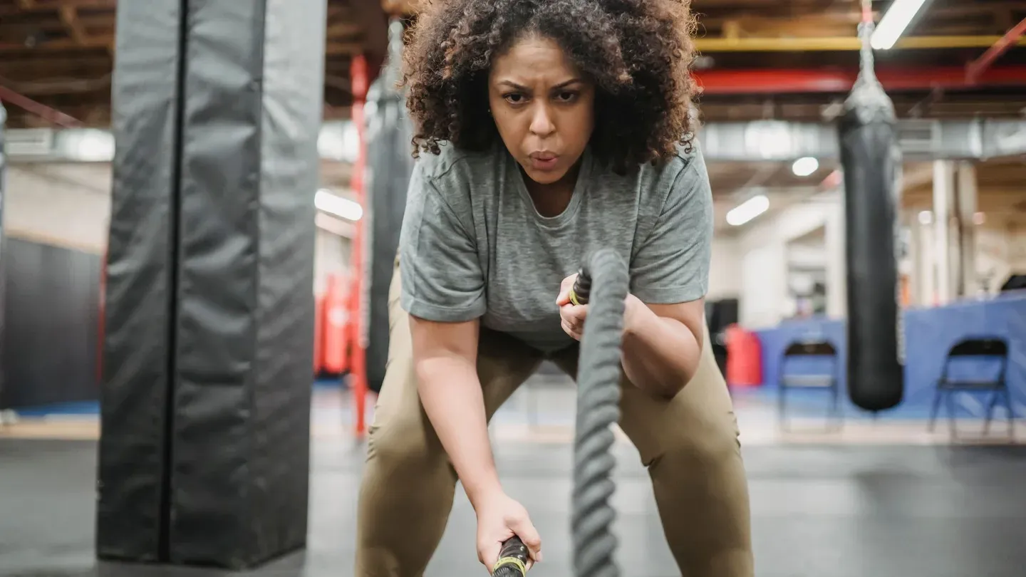Mulher treinando com corda naval (battle rope) em academia Mulher treinando com corda naval (battle rope) em academia