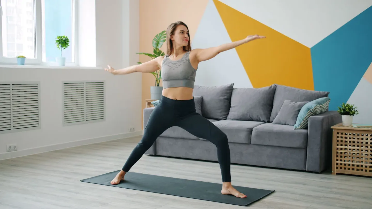 Mulher praticando postura do guerreiro em tapete de yoga em casa Mulher praticando postura do guerreiro em tapete de yoga em casa