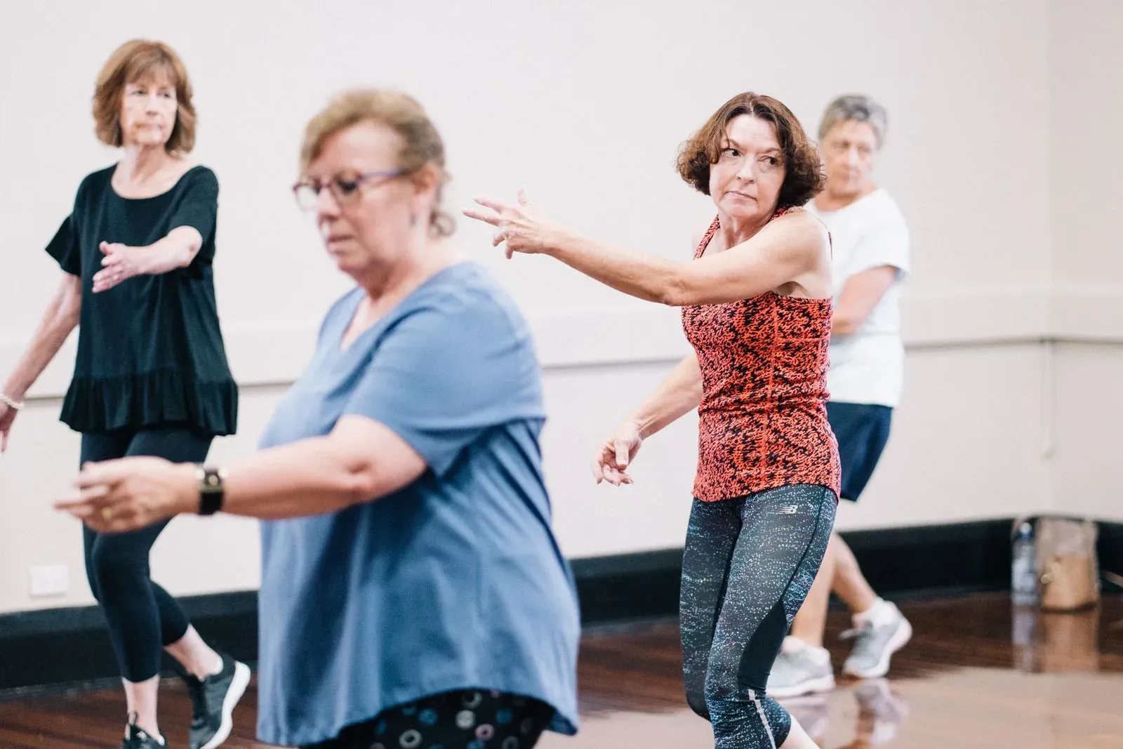 Grupo de mulheres 60+ dançando em aula de fitness, em movimento e sorrindo