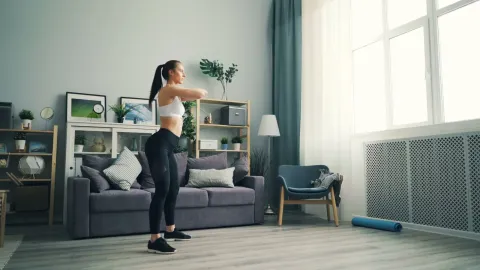 Mulher fazendo exercício cardio de baixo impacto, sem salto e sem equipamento, na sala de casa