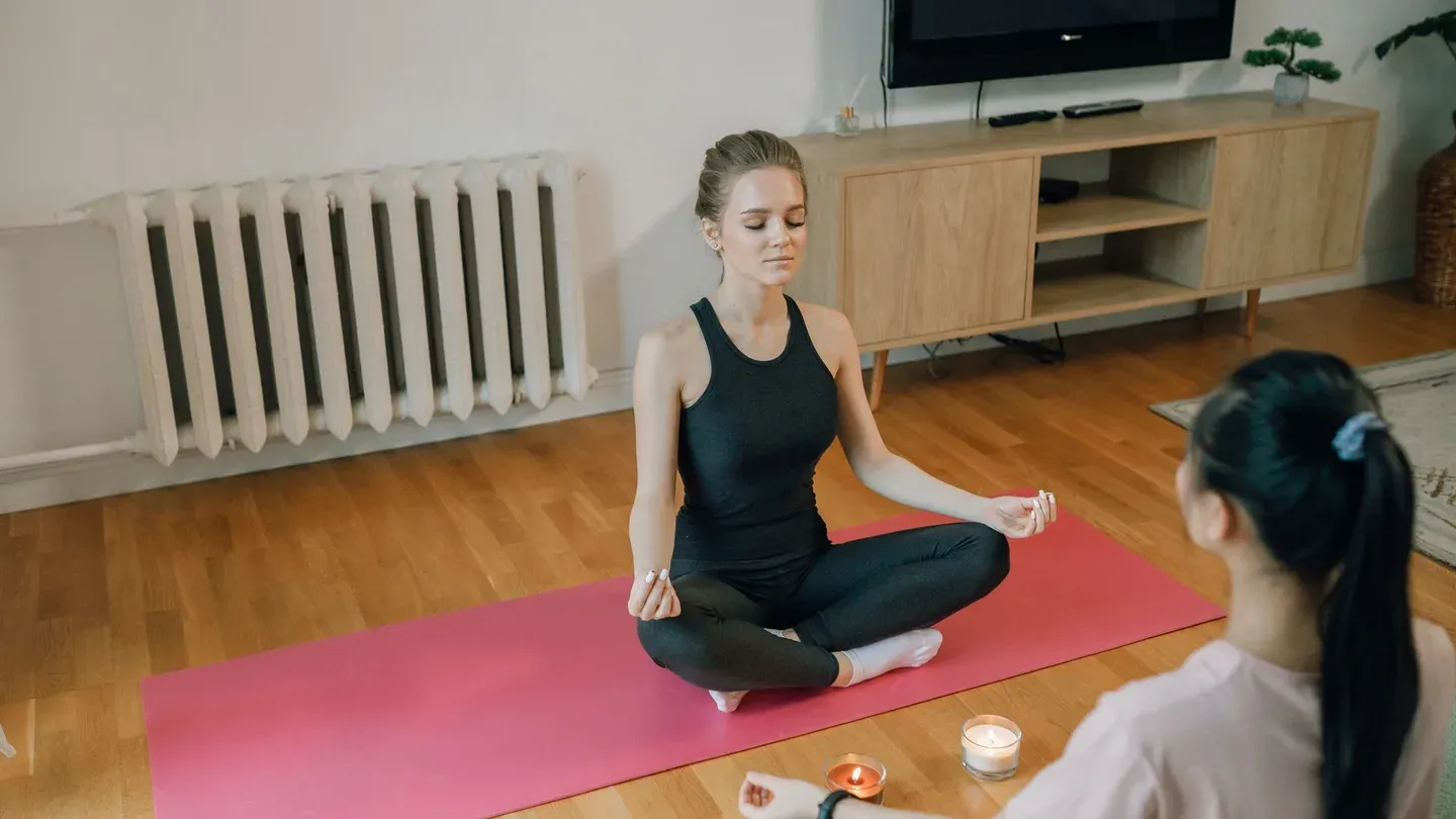 Mulher sentada em postura de meditação sobre tapete de yoga