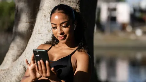 Mulher sorrindo enquanto olha o celular após o treino