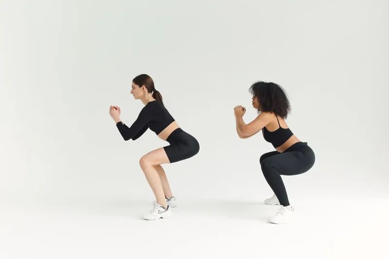Duas mulheres executando agachamento livre lado a lado, exercício funcional composto Duas mulheres executando agachamento livre lado a lado, exercício funcional composto