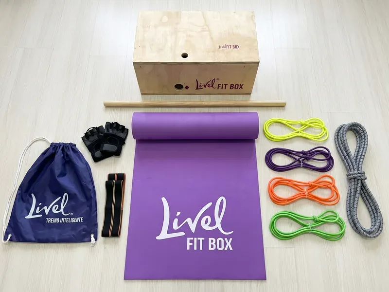 Componentes do Kit FitBox Livel dispostos em flat lay: caixa, elásticos, colchonete, manoplas, bag