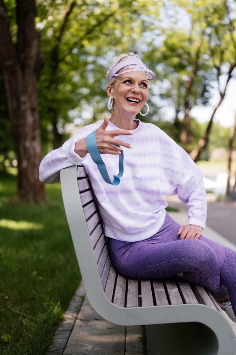 Mulher acima de 60 anos sentada usando elástico de resistência ao ar livre Mulher acima de 60 anos sentada usando elástico de resistência ao ar livre