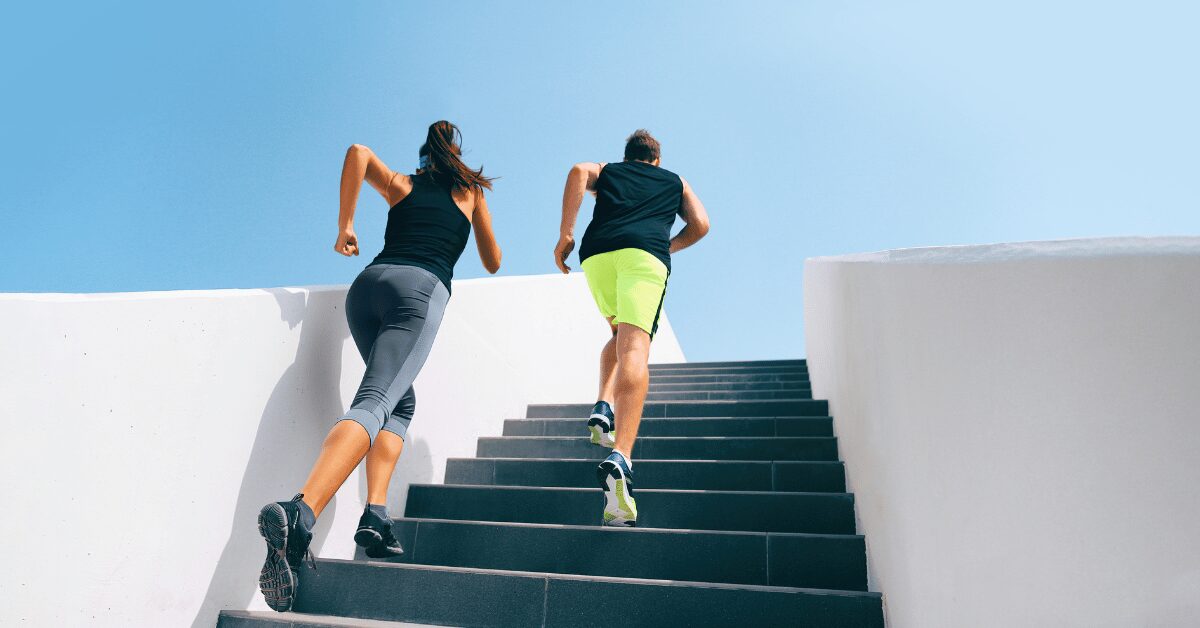 casal subindo escada cinza com roupa de exercicio