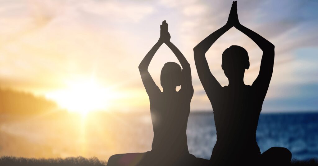 duas pessoas fazendo yoga no por do sol