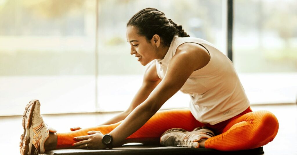 mulher de calça laranja se alongando
