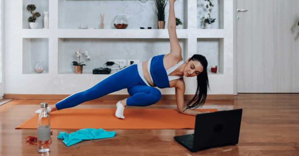 mulher de leg azul fazendo exercicio na frente do laptop