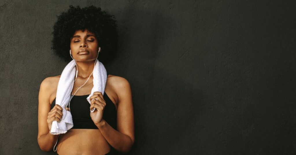 mulher ouvindo musica na parede com toalha branca no ombro