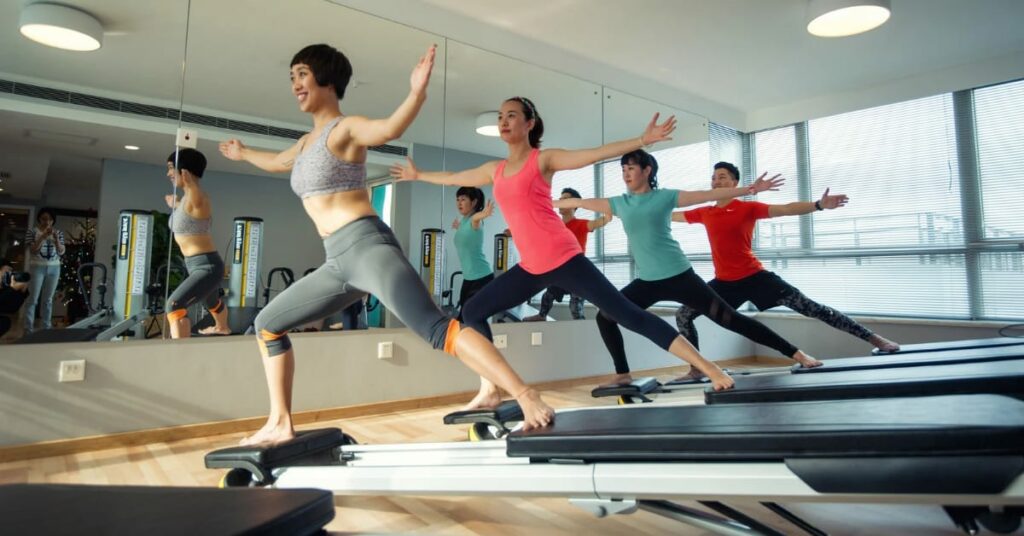 grupo de pessoas fazendo pilates em frente ao espelho