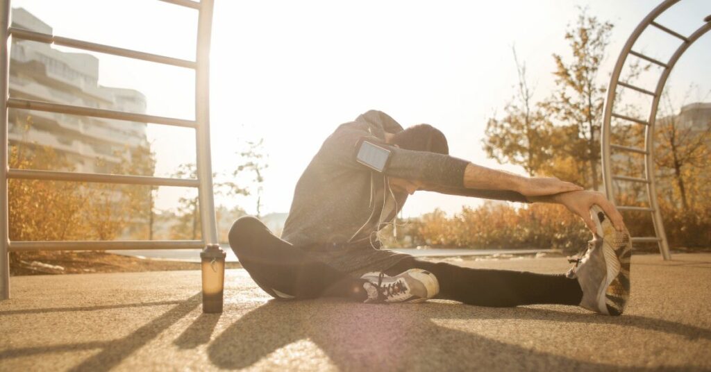 homem fazendo alongamento na praça