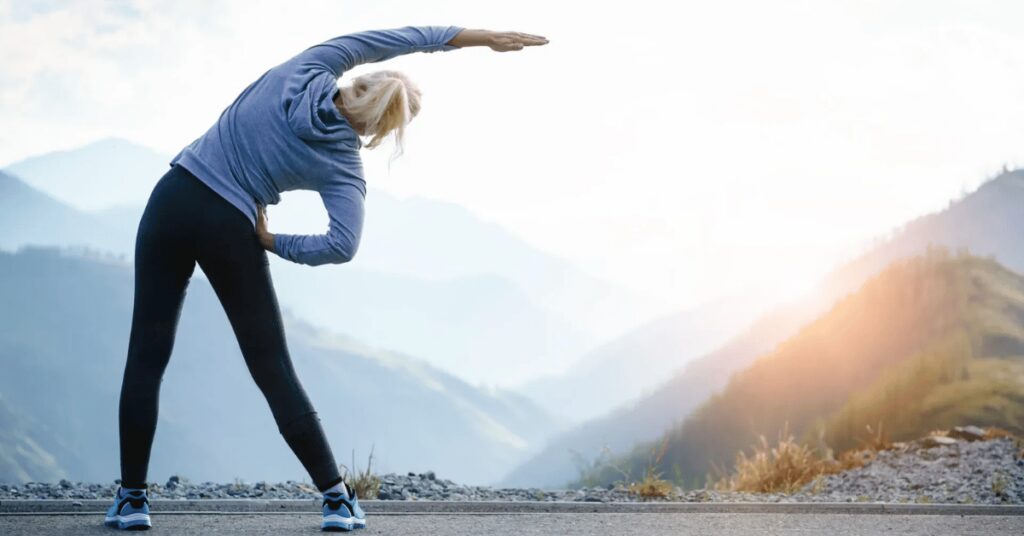 mulher alongando na frente das montanhas