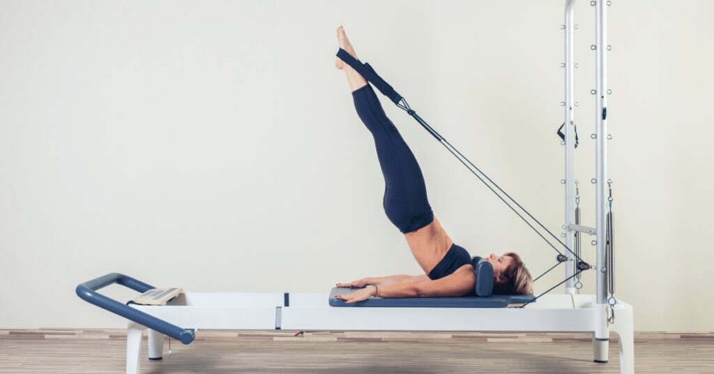 mulher fazendo exercicio com equipamento de pilates
