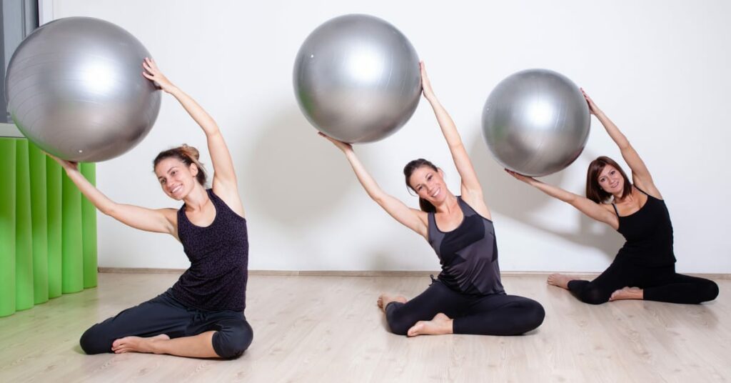 trio de mulheres fazendo pilates com bola