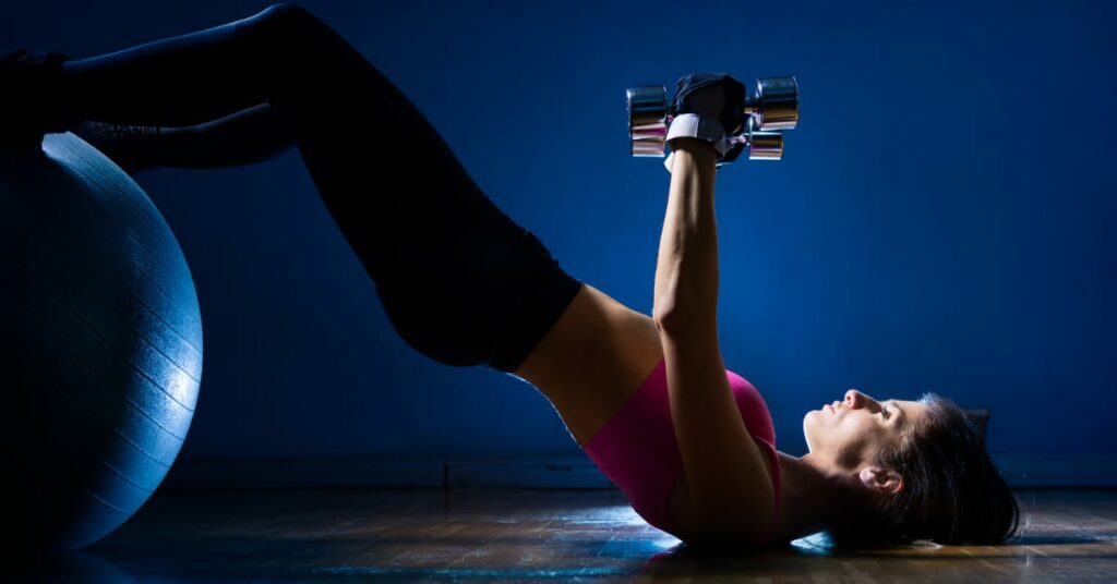 mulher fazendo pilates com pés sobre a bola